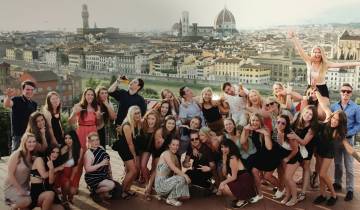 Group of people posing with a panoramic city view in the background.
