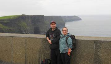 Two people posing by the Cliffs of Moher.