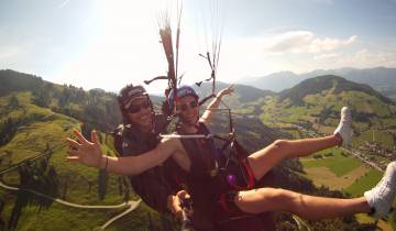 Two people paragliding over a scenic landscape.