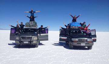 Group of people on SUVs in a white salt flat environment.