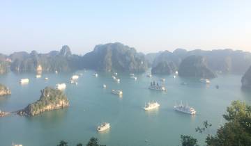 Scenic view of multiple boats sailing in a bay surrounded by limestone hills.