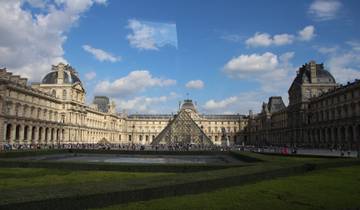 The Louvre Museum courtyard with the glass pyramid surrounded by historic buildings and a crowd of visitors.