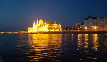 Illuminated building by a river at night.
