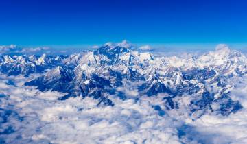 Majestic mountain range with clouds in a clear blue sky.