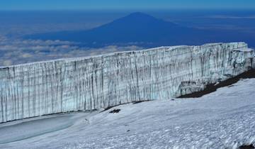 Snow-capped glacier with a distant mountain under a clear sky.