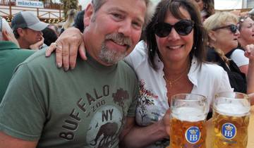Couple smiling with large mugs of beer at an outdoor festival.