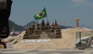 Sand sculpture with a Brazilian flag and small Christ the Redeemer figure.
