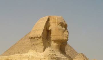 Profile view of the Sphinx with a pyramid in the background.