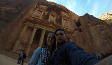 A couple taking a selfie in front of a monumental rock facade.