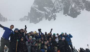 Group of people posing in snow in front of a rocky mountain