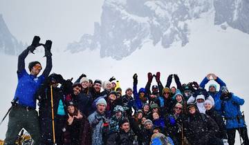 Group of people posing in deep snow with rocky mountains