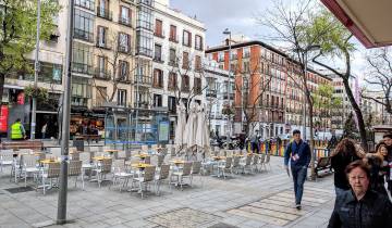 Street in a city with outdoor seating and people walking.