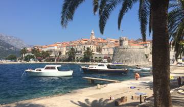 Coastal town with fortification and boats docked along the water.