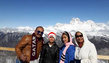 Family posing with snow-covered mountains in the background.
