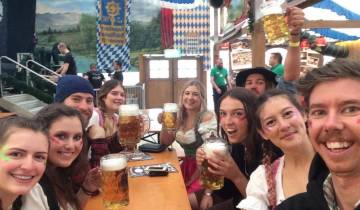 Group of people enjoying beers inside a festively decorated hall.