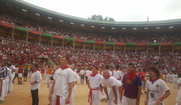 Crowded stadium with people in traditional red scarves.
