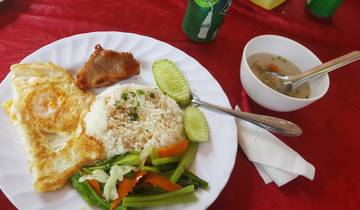Plate of food with rice, vegetables, and meat on a red tablecloth.