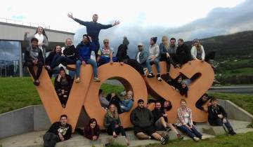 Group of people gathered around the VOSS sign.
