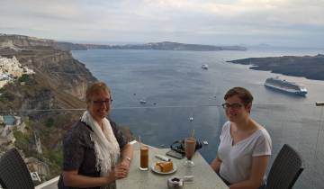 Two people dining with a stunning view of the sea and cliffs.