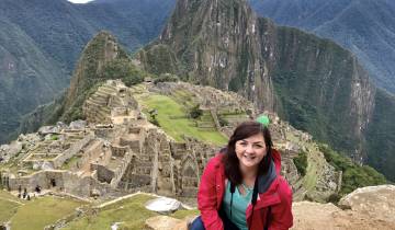 A woman smiling with Machu Picchu ruins in the background.