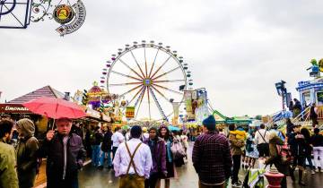 Large crowd at an outdoor festival with a Ferris wheel.