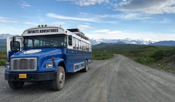 Adventure bus on a scenic road with mountainous landscape.
