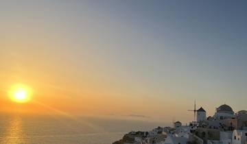 A beautiful sunset over a coastal town with white buildings.