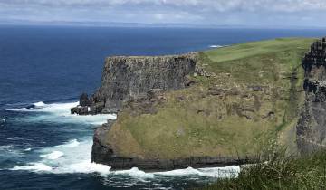 Cliffs meeting the ocean with waves crashing below.