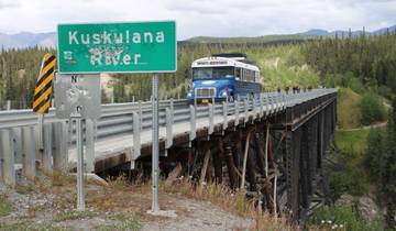 Bridge with a tour bus and a sign for Kuskulana River.