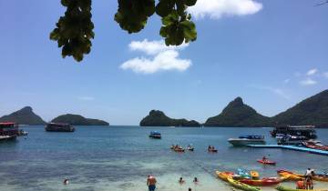 Beautiful beach scene with islands and boats, people in the foreground.