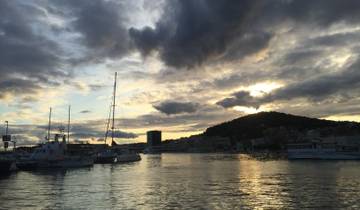 Scenic view of a harbor with boats and dramatic clouds at sunset.