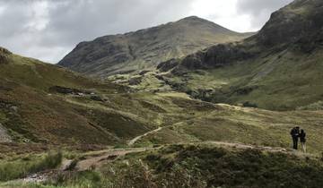 Hiking trail in a lush green valley with mountains.