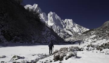 Hikers walking through a snow-covered mountain valley.