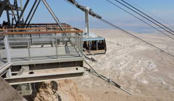 Cable car approaching a station with an expansive desert view.