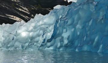 Close-up of a blue glacier by the water.