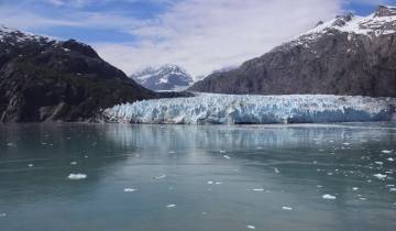Glacier with a lake and mountains in the background.
