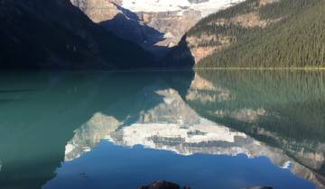 Lake reflecting snow-capped mountains under a clear sky.