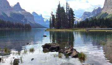 Trees reflecting in a lake surrounded by mountains.