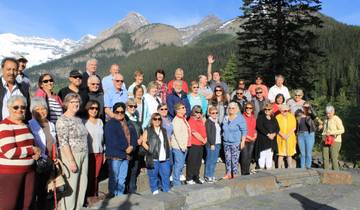 Large group of tourists posing with mountains in the background.