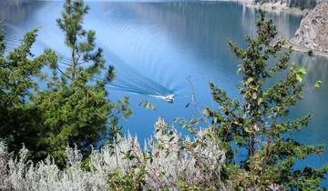 A boat moving through a lake surrounded by trees.