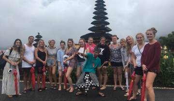 Group standing at a temple with tiered roofs.