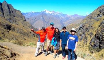 Group of hikers posing on a mountain trail with scenic background.