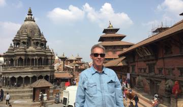 Man posing in front of historic buildings and temples.