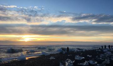Scenic view of icebergs on a beach with a beautiful sunset.