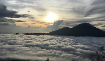Breathtaking view of a mountain range above a sea of clouds at sunrise.