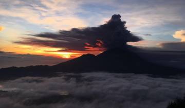Volcanic eruption against a vibrant sunset sky.