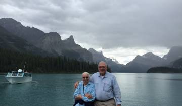 Couple posing by a serene lake with mountain views.
