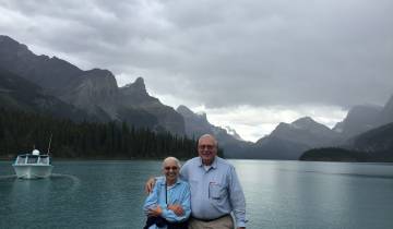 Couple posing by a serene lake with mountain views.
