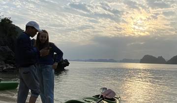 Two people with a kayak on a beach at sunset.