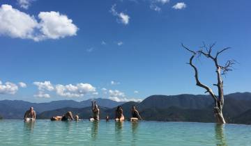 People relaxing in a pool with mountains in the background.